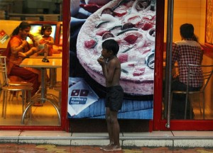 Homeless boy holds biscuits that he received as alms as he takes shelter from rain in Mumbai