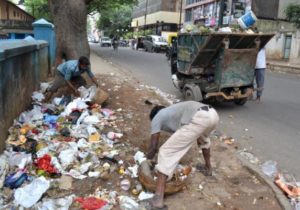 बिना दास्ताने, मास्क और गम बूट के कूड़ा इकट्ठा करते पोराकर्मिका, चित्र साभार: ‘द हिन्दू डॉट कॉम’ 